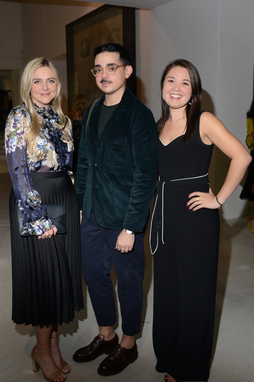 Three people dressed in formal attire posing for a photo at an indoor event.