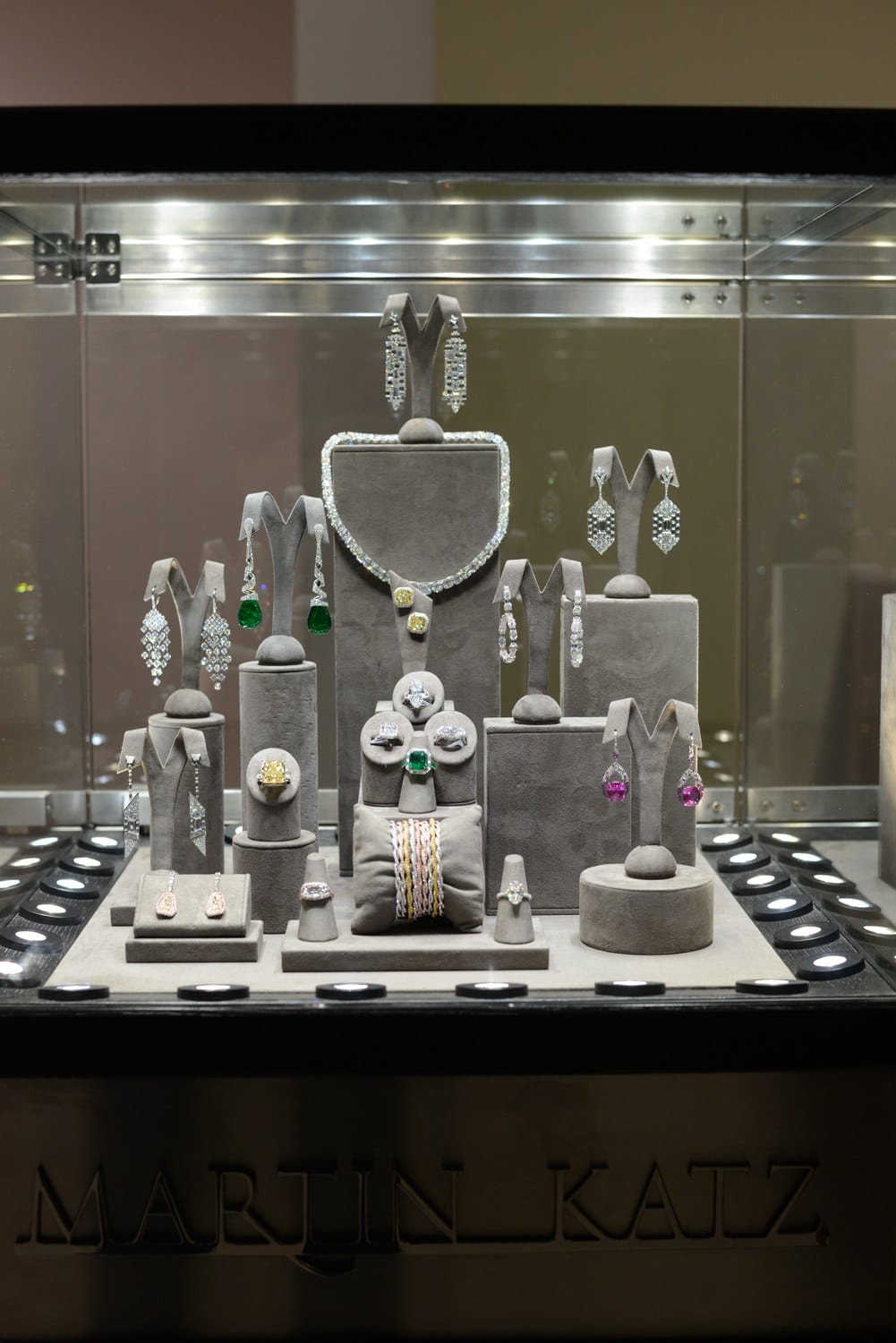 A luxurious jewelry display featuring necklaces, earrings, and rings with various gemstones in a well-lit showcase.