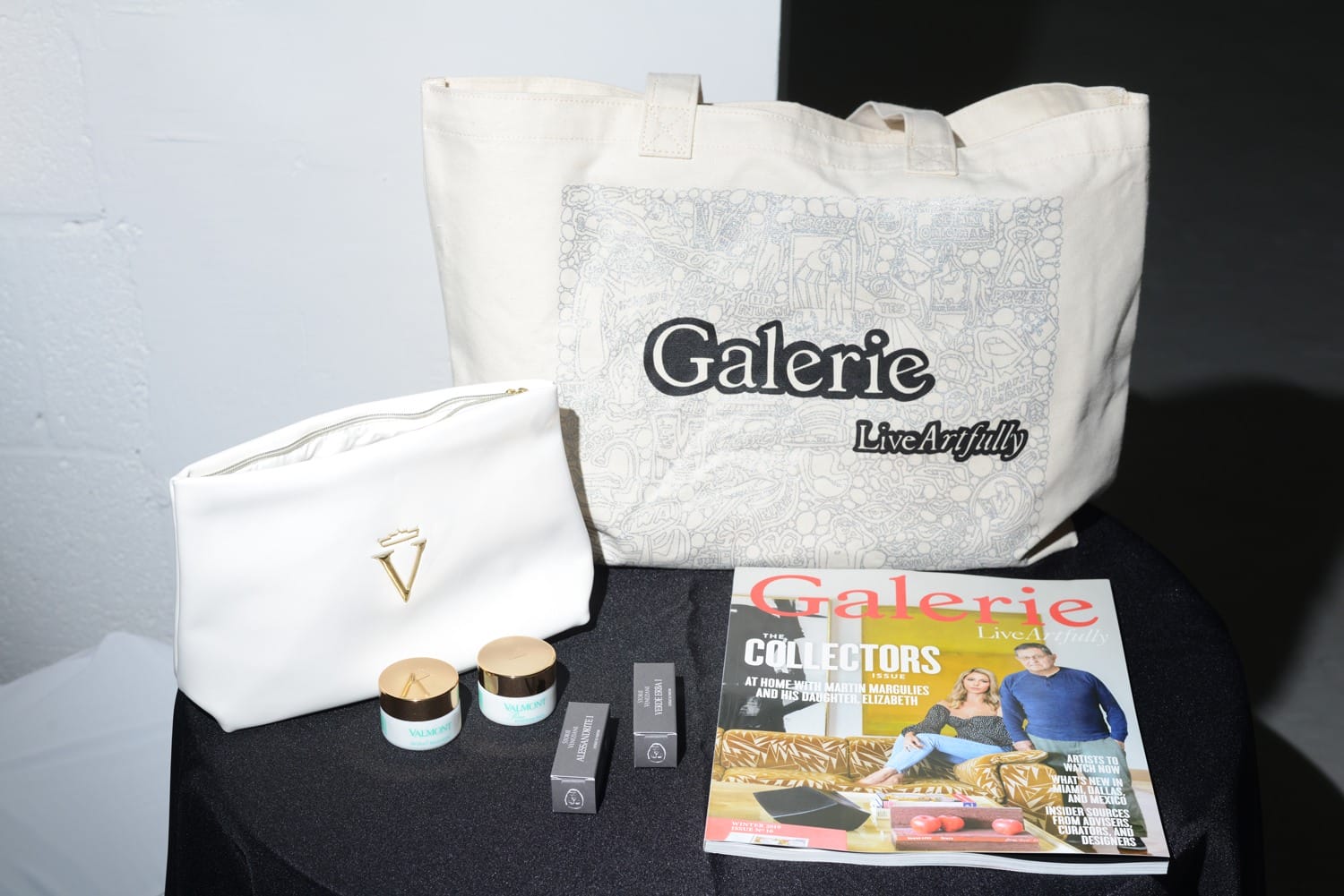 Galerie magazine, tote bag, cosmetic products on a black table.