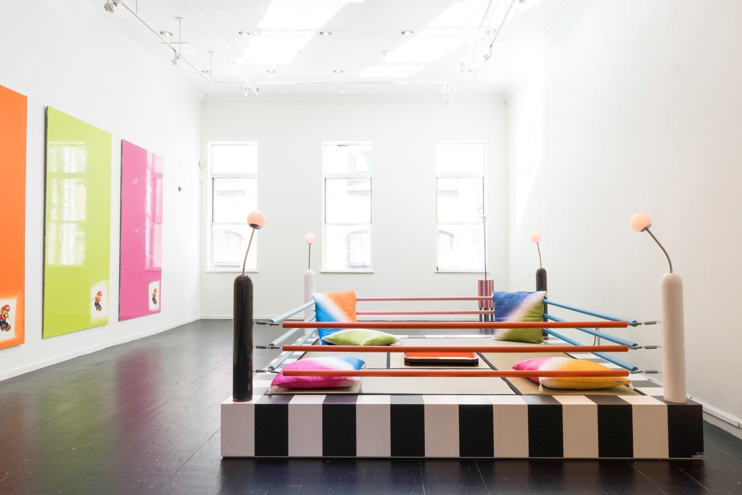 Colorful modern art installation with a playful boxing ring setup, bright cushions, and vibrant floor-to-ceiling artworks.