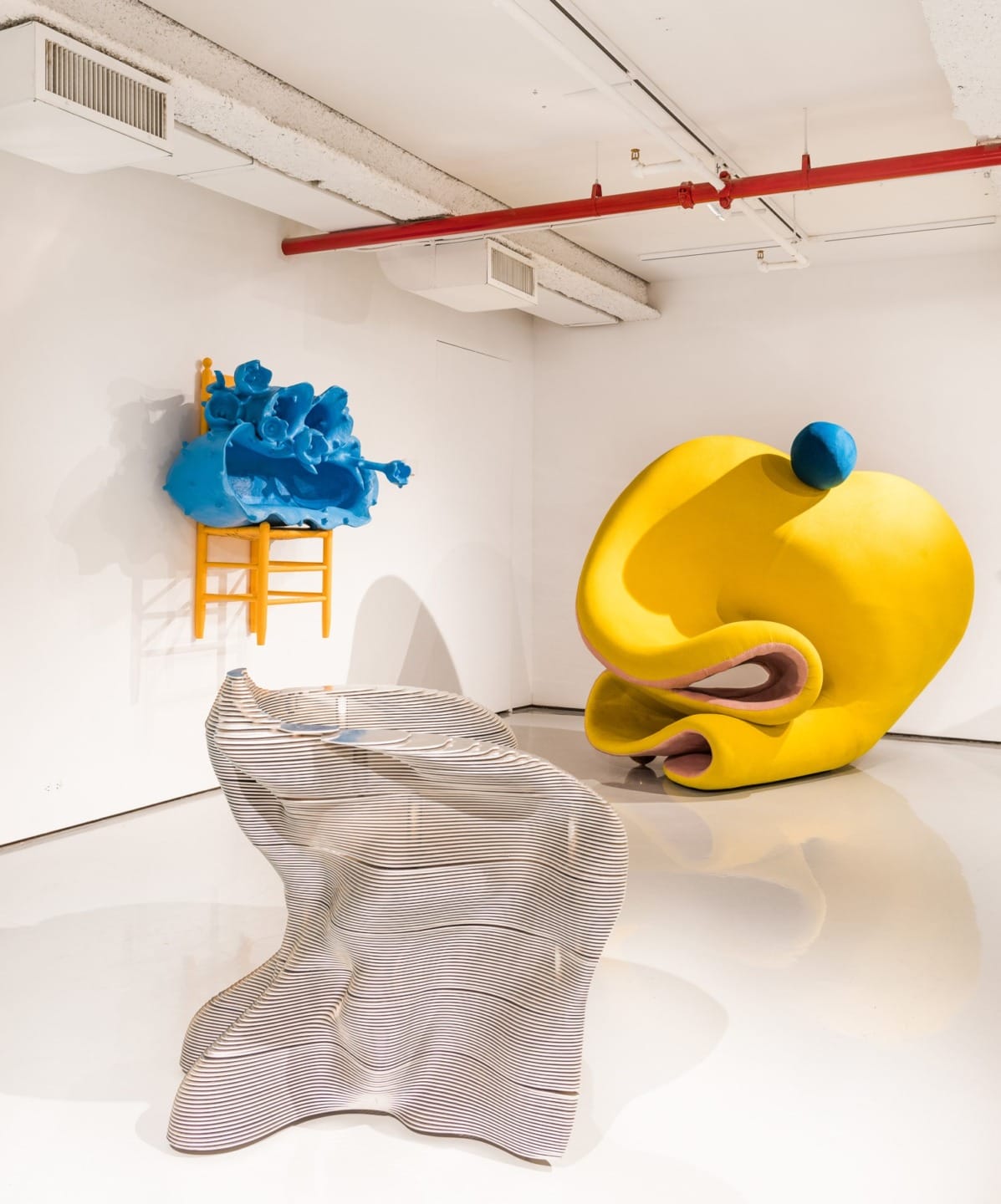 Colorful abstract sculptures in a modern gallery with white walls and a polished floor.