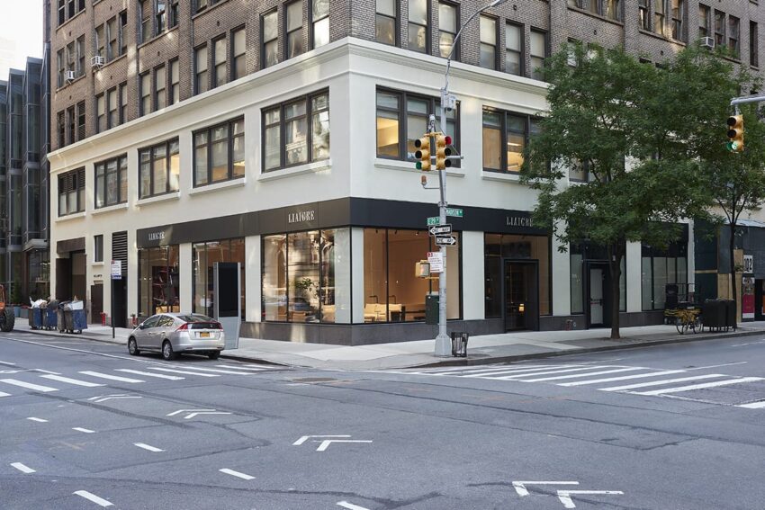 Street corner with a multi-story building featuring a Ladurée storefront, a tree, and a parked car on a city street.