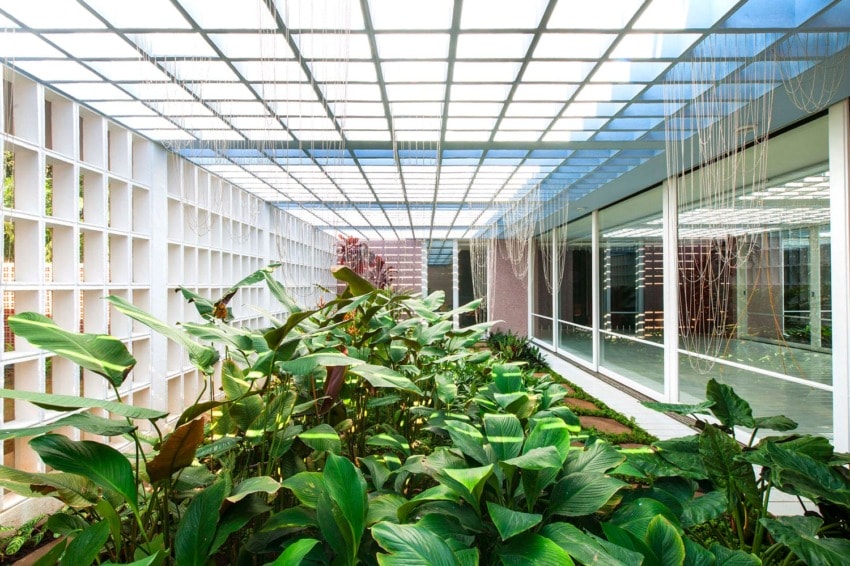 indoor garden with lush green plants under a grid-like glass ceiling and modern architectural elements