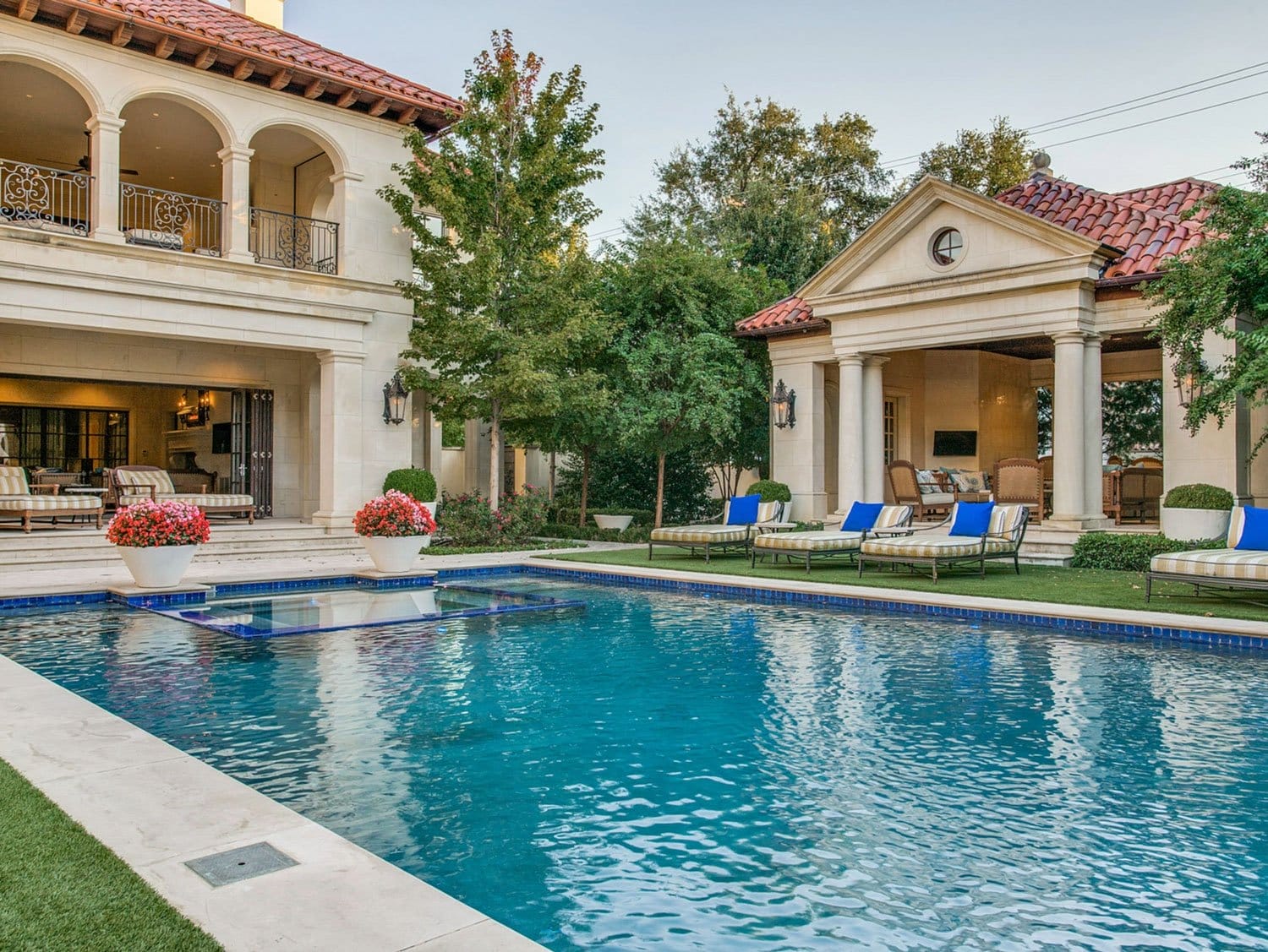 Luxury villa with outdoor pool, lounge chairs, and lush greenery in a Mediterranean-style setting.