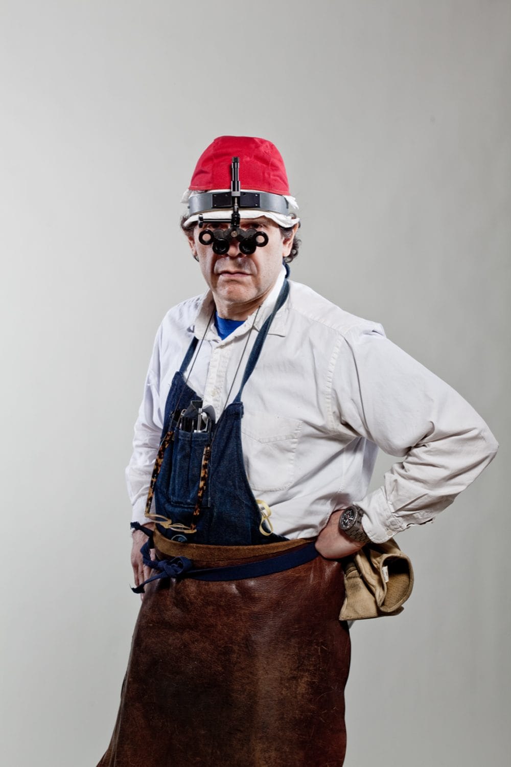 Person wearing a red hard hat, headlamp, and apron, posing against a plain background.