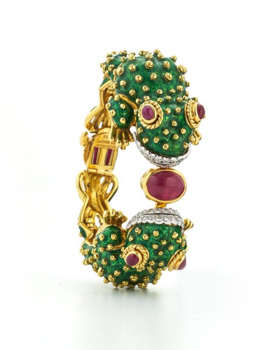 Gold bracelet with green textured design and red gemstones, resembling two facing animal heads, displayed on a white background.