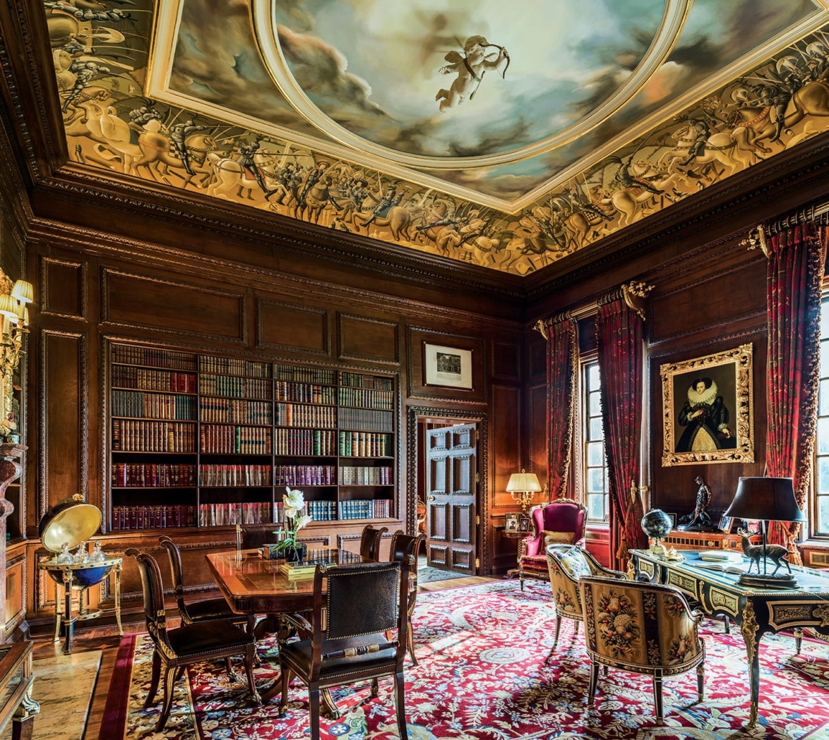 Luxurious library with ornate wooden shelves, detailed ceiling art, vintage furniture, vibrant red carpet, and large windows.