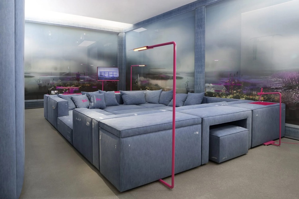 Modern living room with a large blue sectional sofa, pink lamps, and abstract window view.