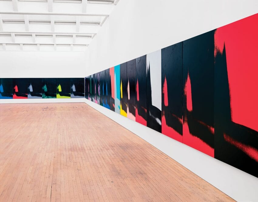 Contemporary art exhibition in a spacious gallery with colorful abstract paintings on the walls.