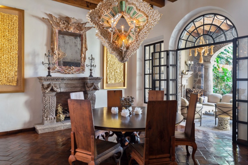 Elegant dining room with wooden table, ornate chandelier, and open doors leading to a lush garden patio.