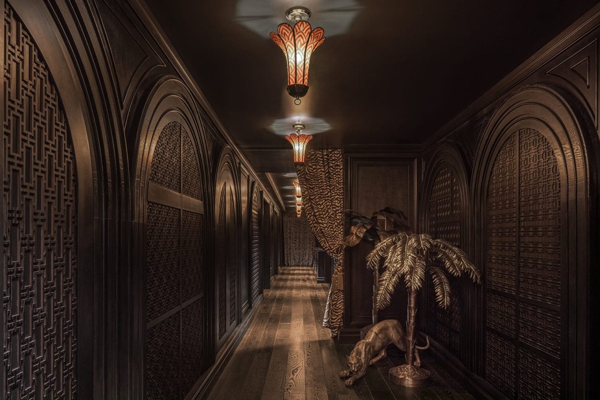 Dimly lit ornate hallway with decorative woodwork, stained glass chandeliers, and a detailed tiger wallpaper.