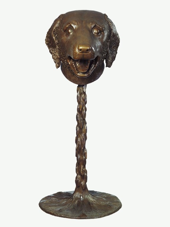Bronze sculptural artwork of a dog's head with an elongated neck as a stand, on a simple base against a light background.