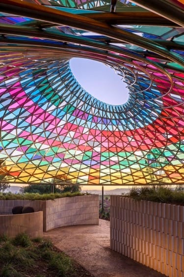 Colorful geometric dome with vibrant stained glass panels, creating a kaleidoscope effect under a clear sky.