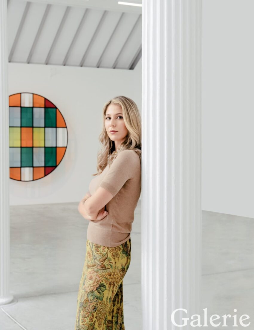 Person standing near a white pillar in an art gallery with colorful circular artwork in the background