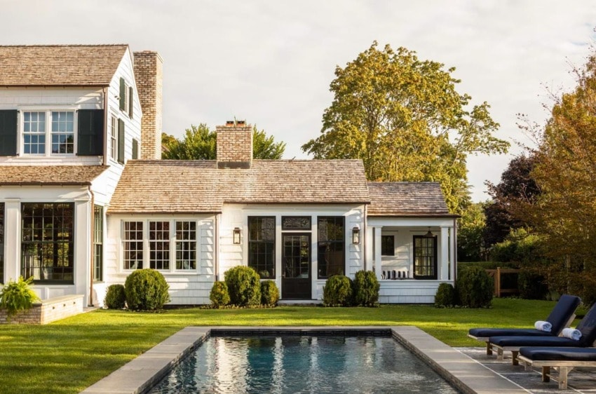 Charming white house with a pool, surrounded by greenery, showcasing classic architecture and a serene outdoor setting.