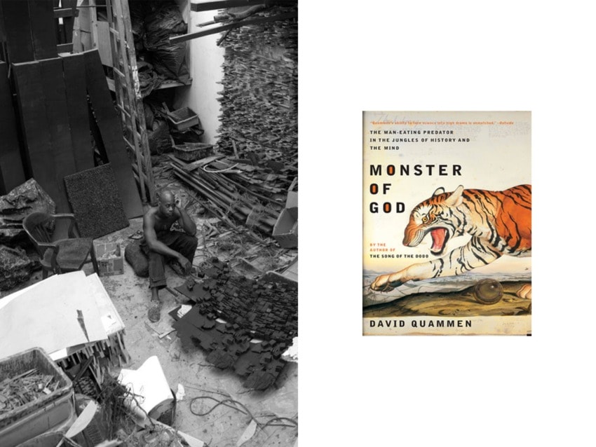 A man sitting in an art studio filled with supplies; a book titled "Monster of God" featuring a tiger on the cover.