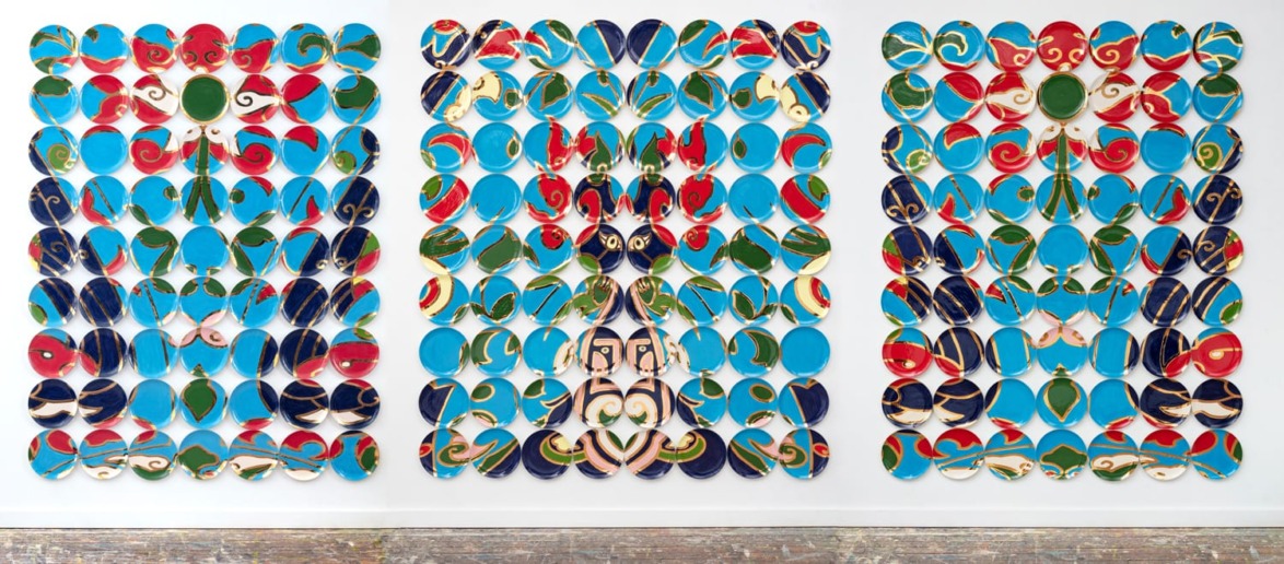 Abstract artwork with colorful painted stones arranged symmetrically in three panels, featuring blues, reds, and greens.