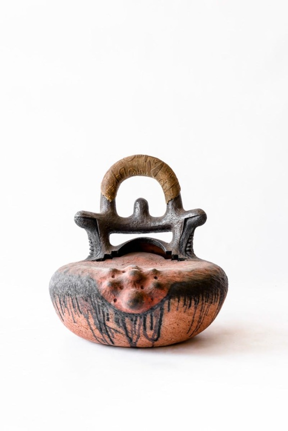 Ceramic sculpture with intricate design, featuring a textured surface and carved handle against a plain white background.