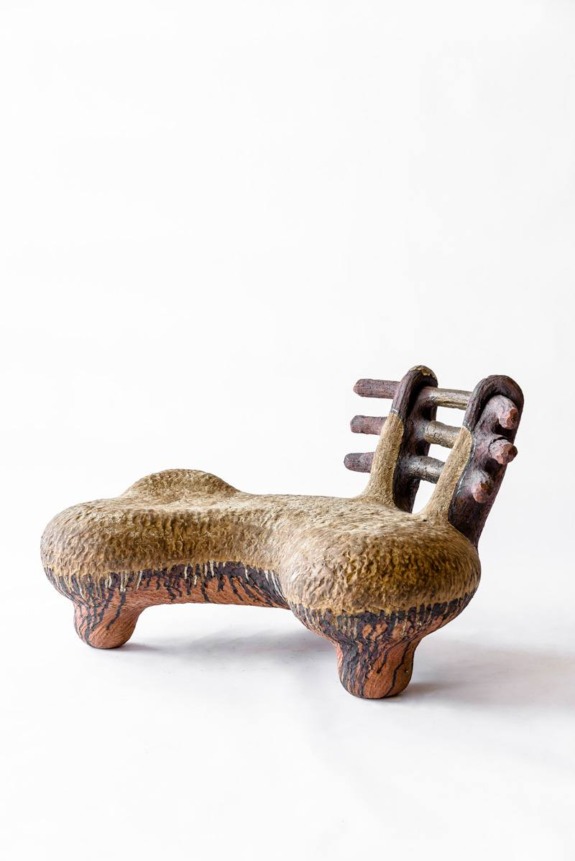Unique wooden chair with abstract design, rustic texture, and curved seat on a white background.