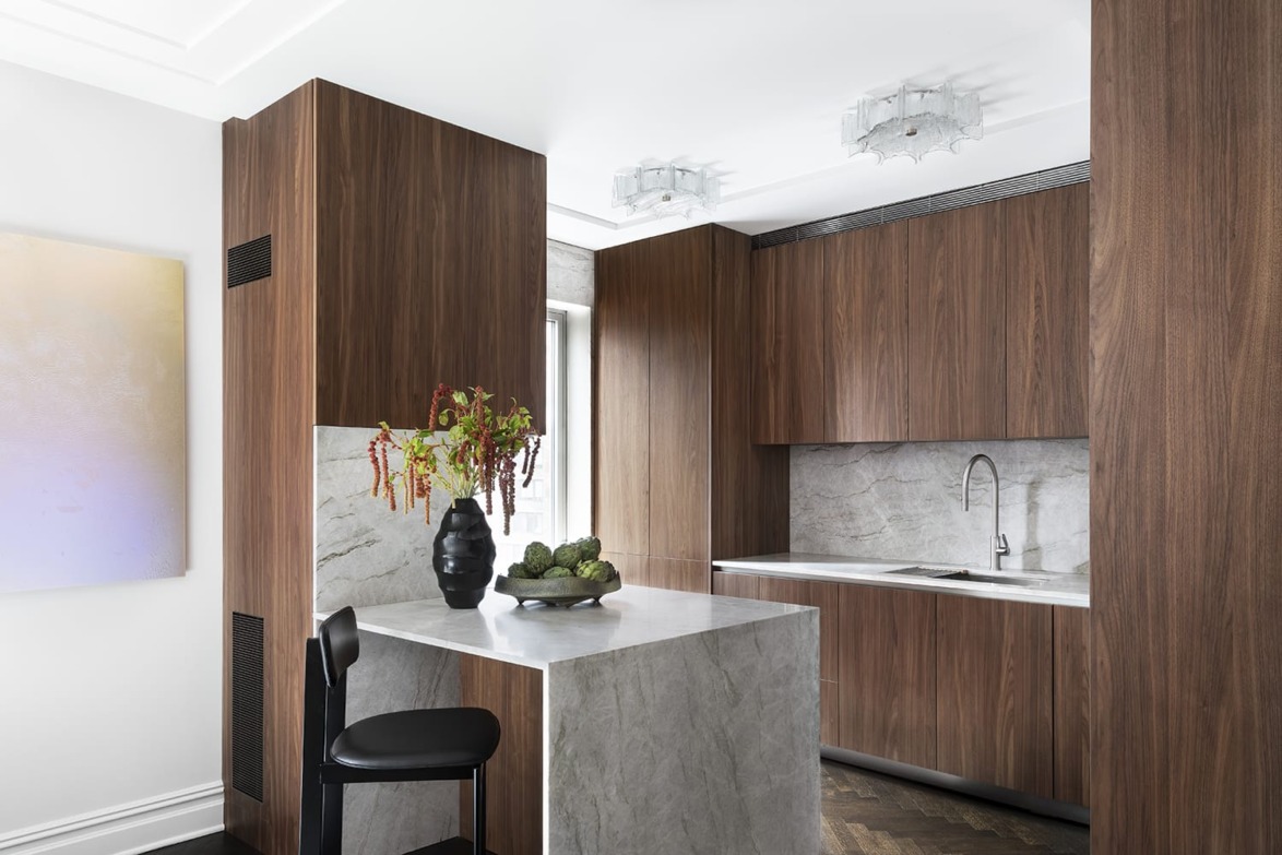 Modern kitchen with dark wood cabinets, marble countertop, and decorative plants in a vase.
