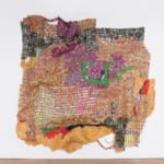 Colorful abstract tapestry art with vibrant geometric patterns hanging on a white wall.