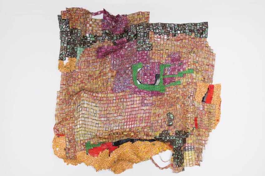 Colorful abstract tapestry art with vibrant geometric patterns hanging on a white wall.