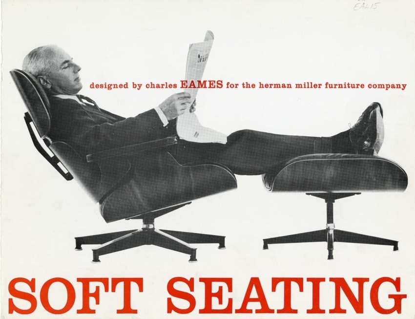 Black and white photo of a man reclining in a classic Eames chair, reading a newspaper.