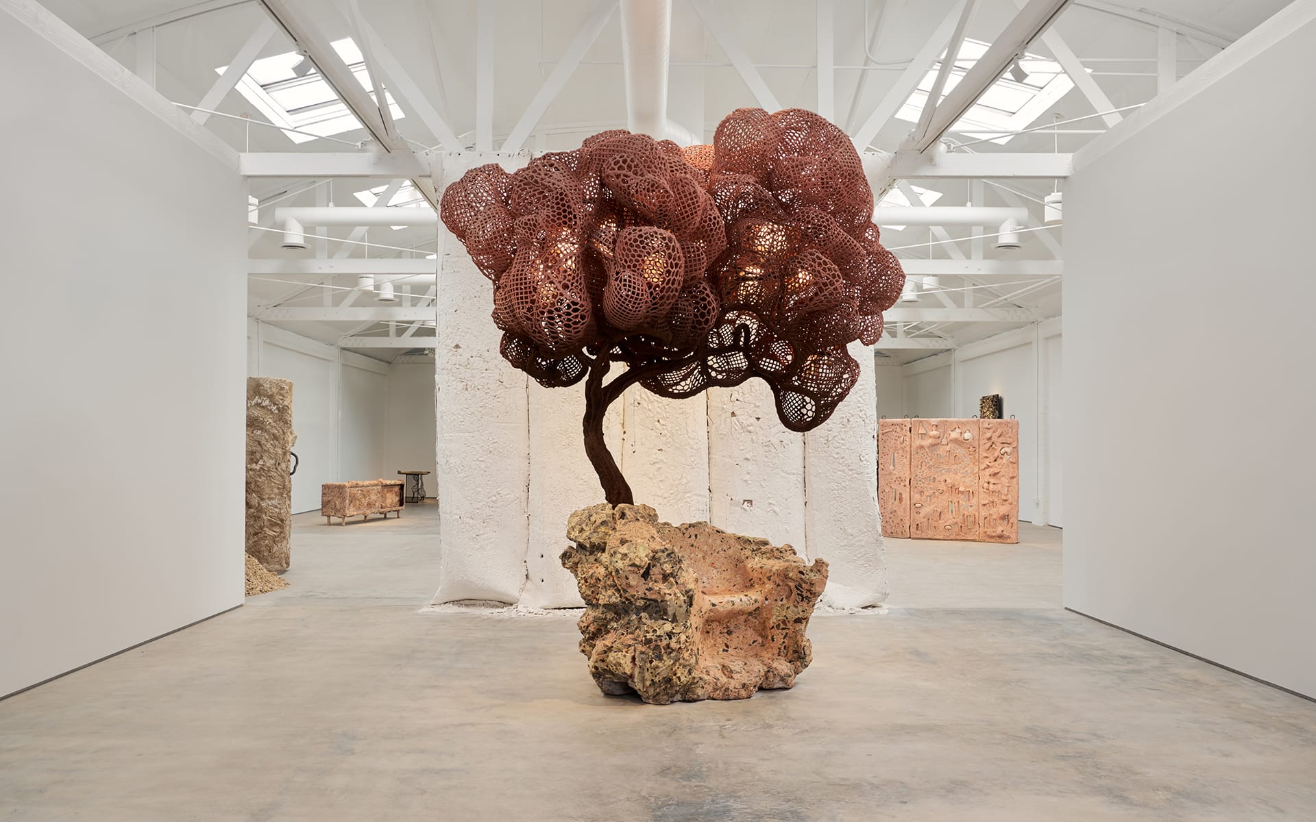 Large sculptural artwork resembling a tree with intricate, round formations on display in a spacious, modern gallery setting.