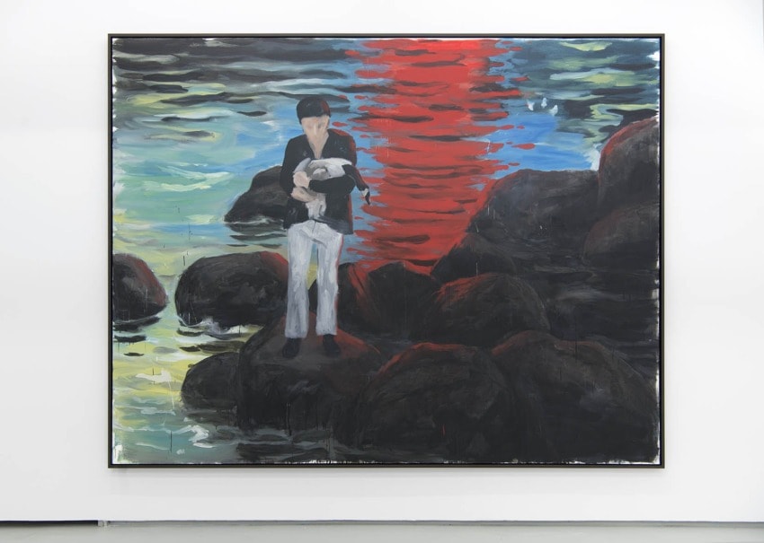 Painting of a person standing on rocks by water, holding a bird against a vibrant red and blue reflective sky.