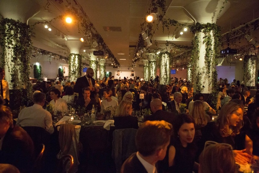 People dining in a dimly lit, elegant venue with ivy-covered pillars and ambient lighting.
