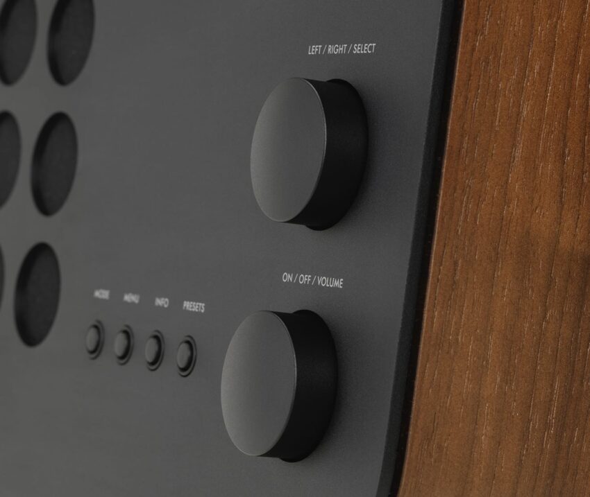Close-up of a wooden audio device with two large control knobs labeled for selecting and volume adjustment.