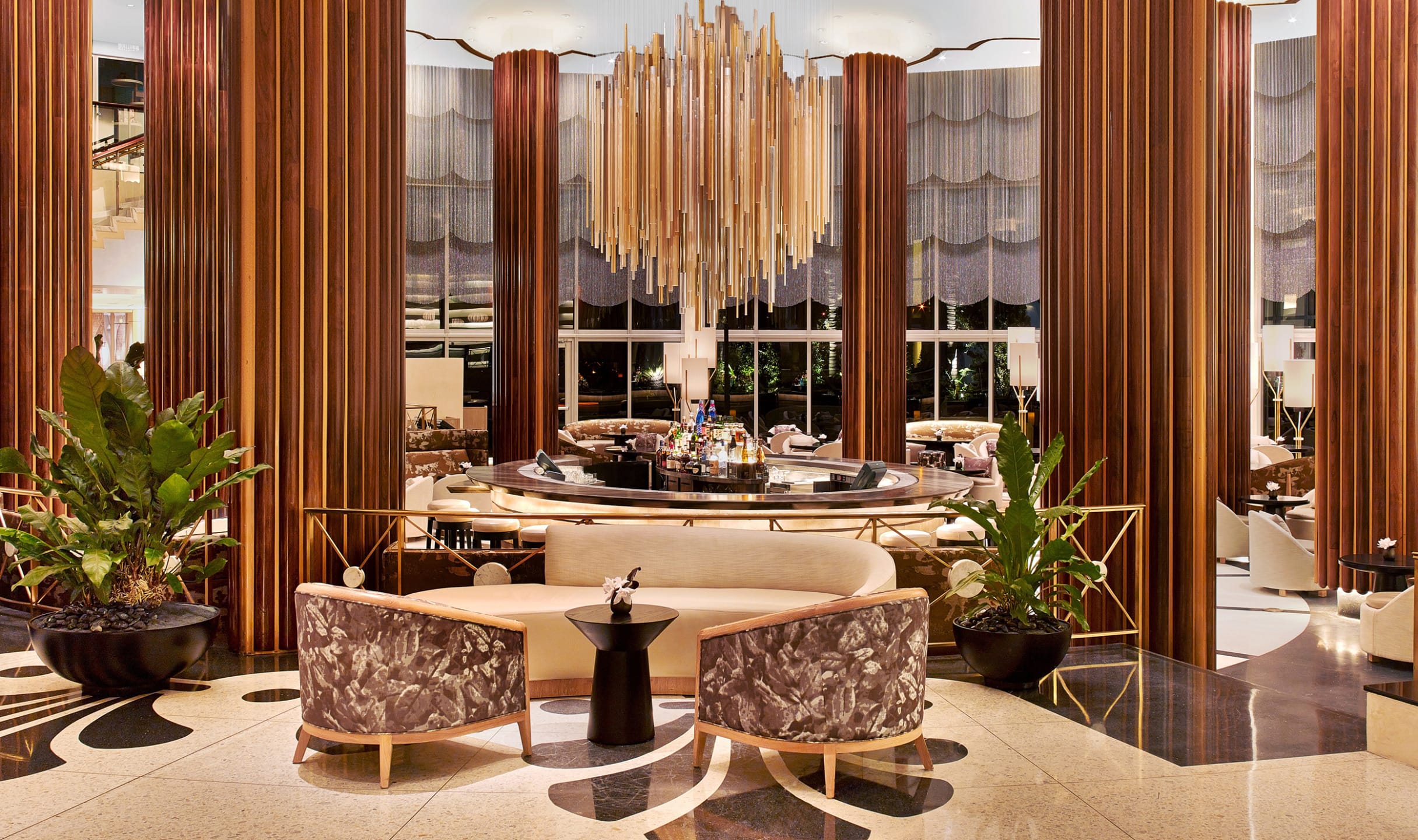 Luxurious hotel lobby with elegant seating area, large chandelier, wooden columns, and modern decor elements.