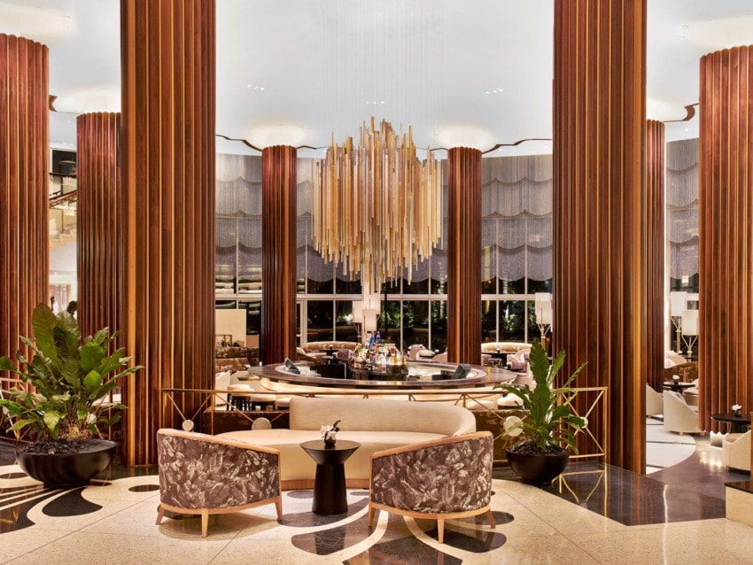 Luxurious hotel lobby with elegant chandelier, plush seating, and large decorative columns.