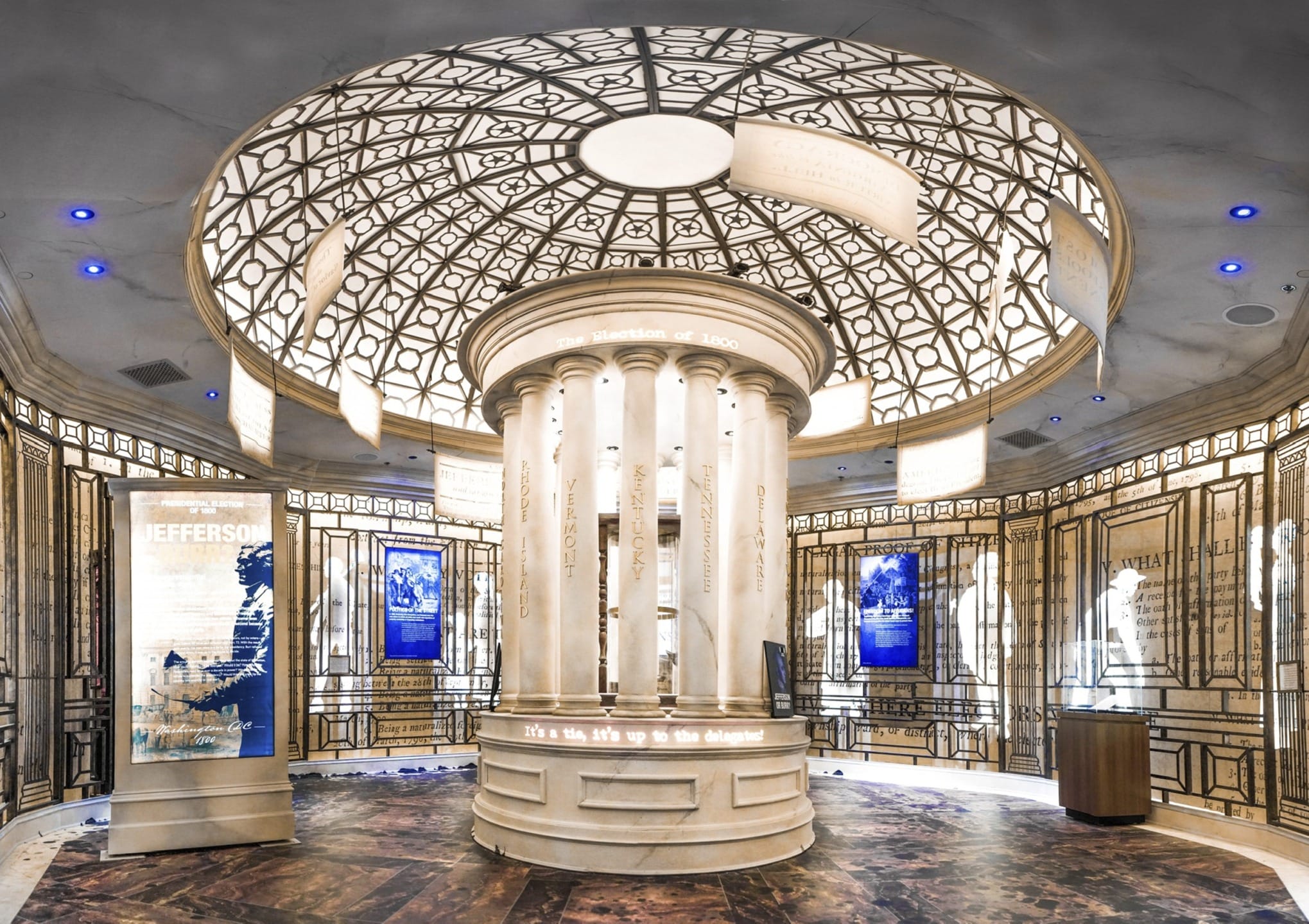 A grand, ornately designed rotunda with decorative columns and digital displays at a museum exhibit.