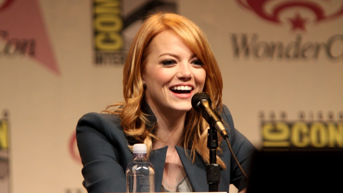 Person speaking into a microphone at a convention panel with a smiling expression.