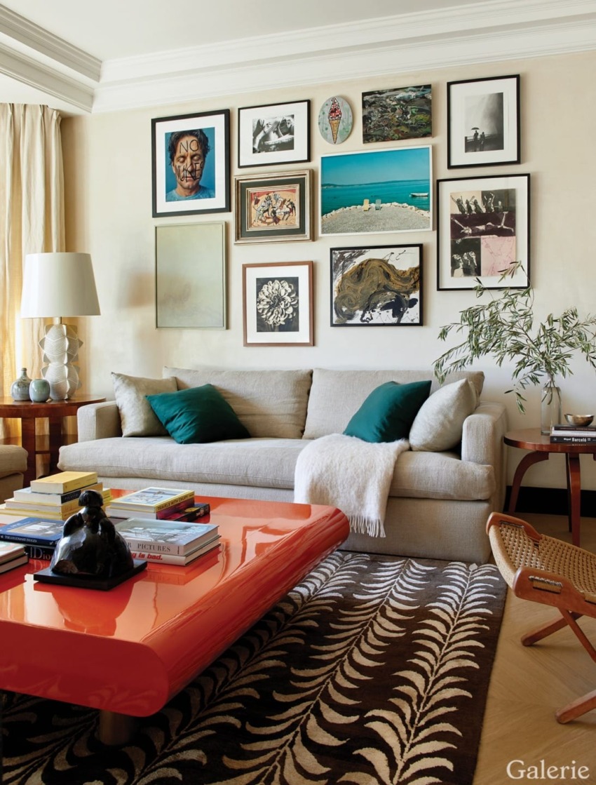 Living room with beige sofa, colorful framed wall art, orange coffee table, and decorative rug.