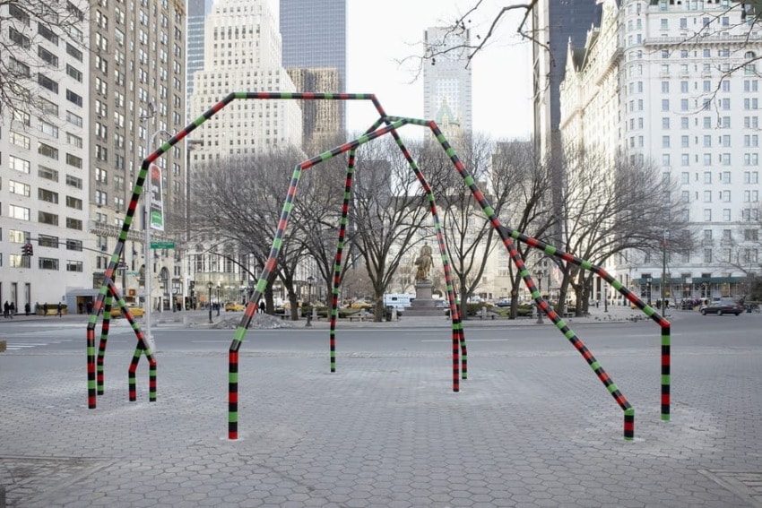 Outdoor colorful sculpture installation in an urban plaza with skyscrapers and bare trees in the background.