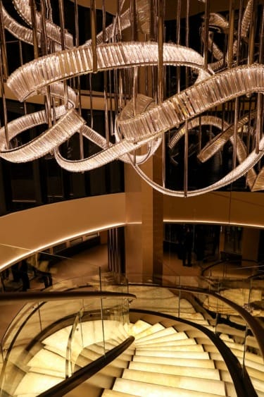 Elegant spiral staircase with a modern, artistic chandelier overhead, creating a luxurious and sophisticated ambiance.