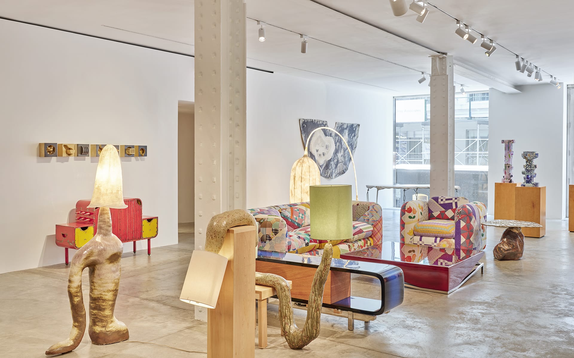 Contemporary art gallery with eclectic sculptures, colorful furniture, and modern lighting fixtures in a spacious room.