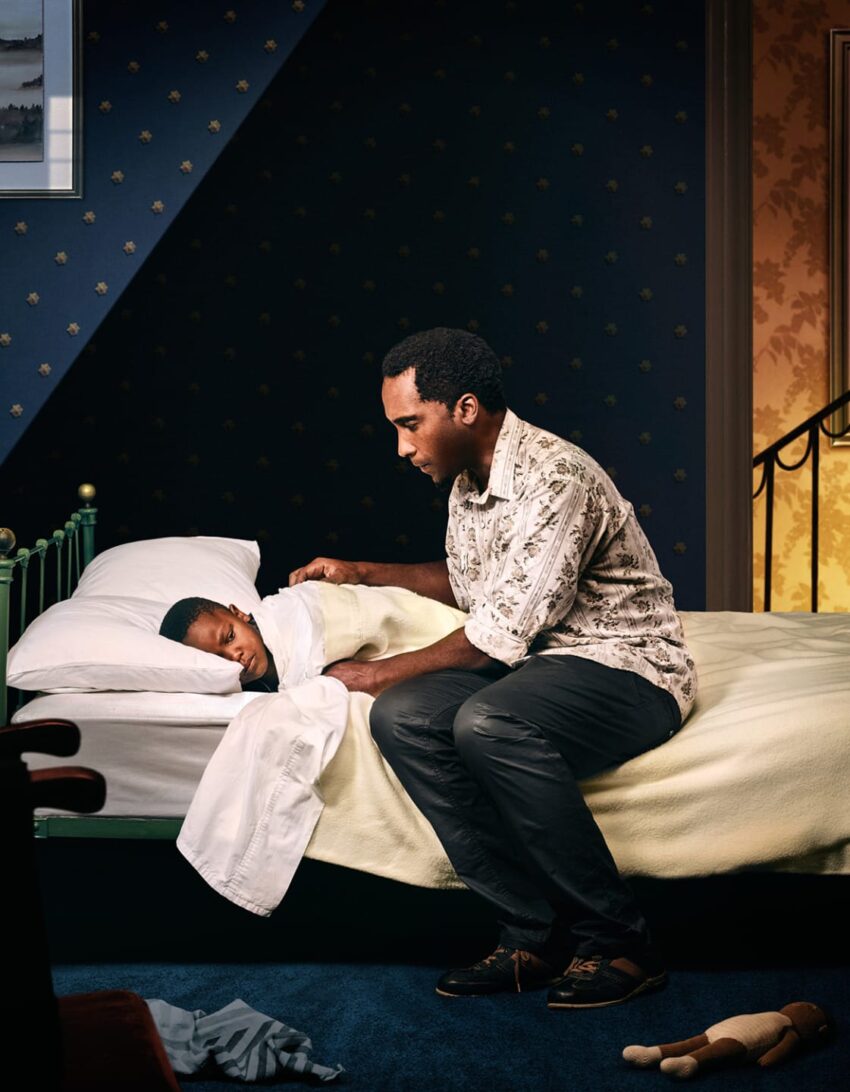 Father tucking his child into bed, ensuring comfort and security in a cozy bedroom setting at night.