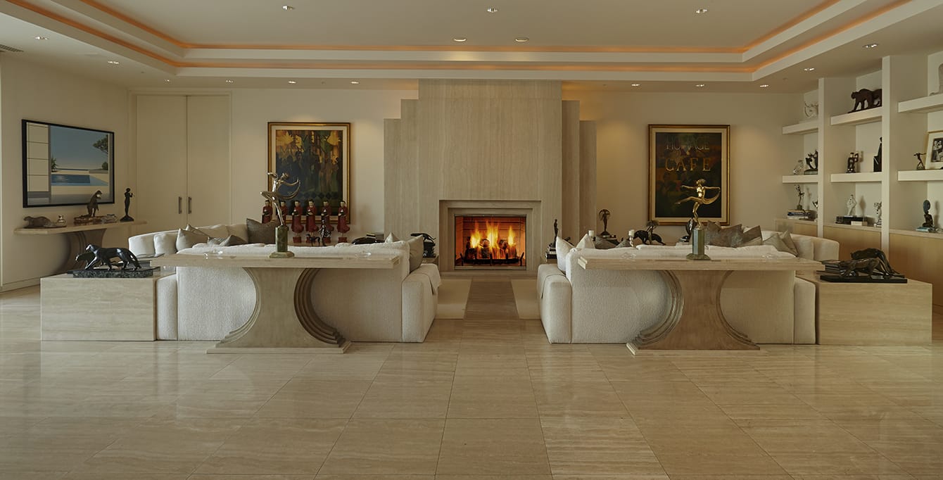 Luxurious living room with marble floors, elegant sofas, a modern fireplace, and artwork on walls.