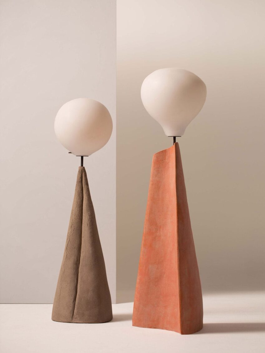 Two modern sculptural lamps with tall conical bases, one brown and one terracotta, topped with round white globes.