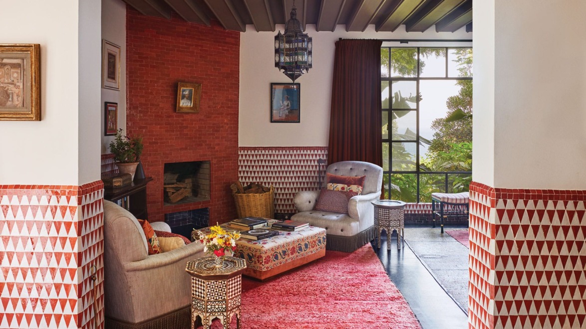 Colorful living room with patterned walls, plush red rug, and cozy seating by a large window.