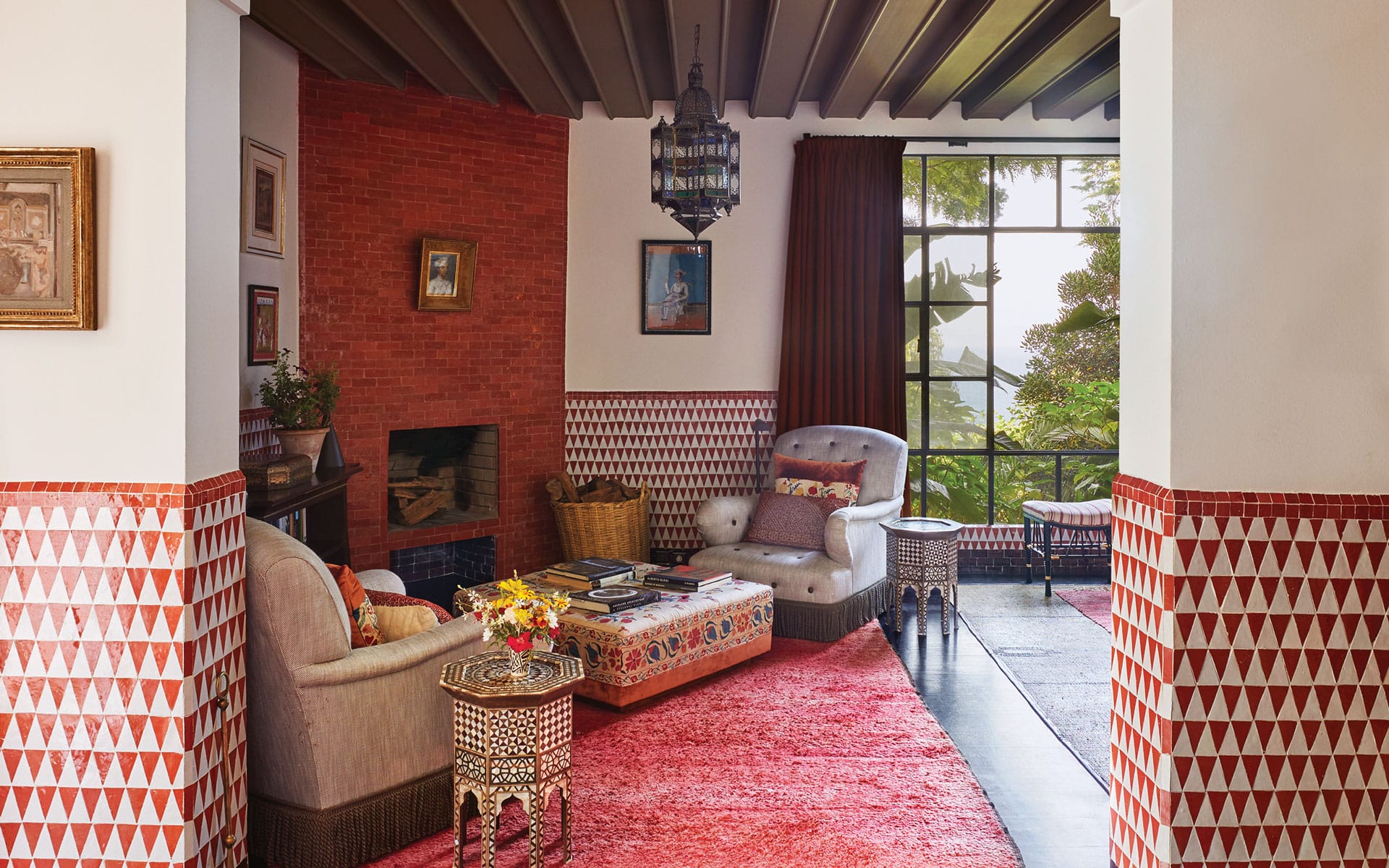 Colorful living room with patterned walls, plush red rug, and cozy seating by a large window.