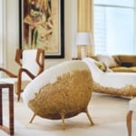 Luxurious living room with a uniquely designed gold and white chair, modern art on the wall, and elegant decor elements.