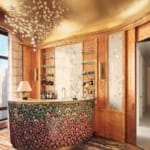 Luxurious home bar with curved counter, elegant glass shelving, gold ceiling, chandelier, and large windows with city view.