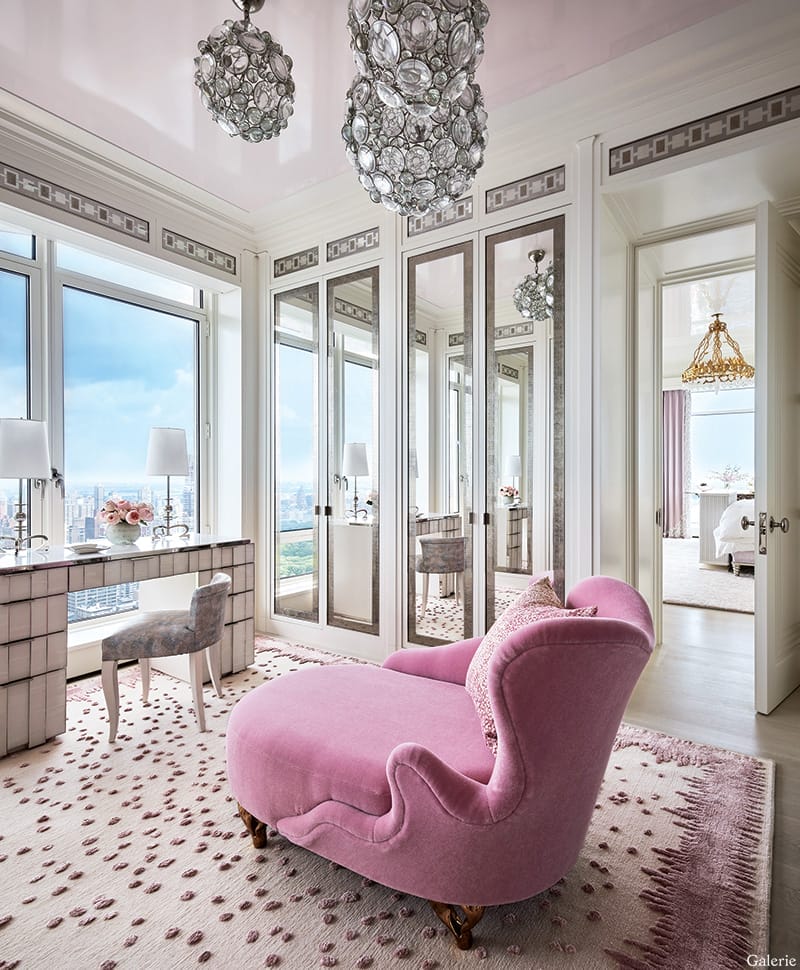 Luxurious room with pink chaise lounge, mirrored wardrobe, large windows, and elegant chandeliers.