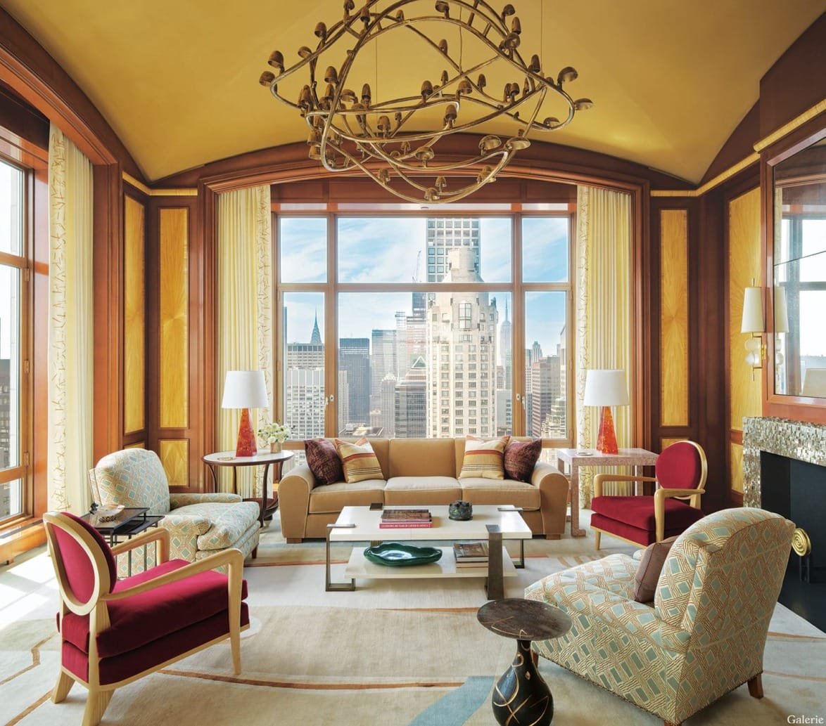 Elegant living room with large windows, modern furniture, unique chandelier, and city skyline view in the background.