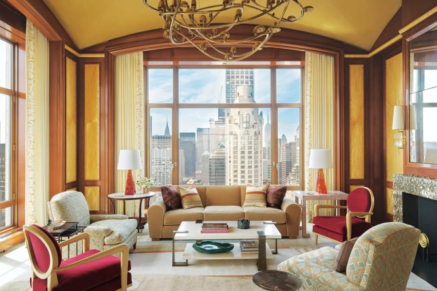 Elegant living room with large windows, modern furniture, unique chandelier, and city skyline view in the background.