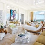 Elegant living room with modern furniture, large windows with a city view, and eclectic decorative elements.